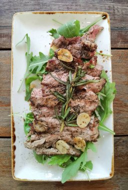 Beyaz tabakta taze sebzeyle kızartılmış domuz eti.