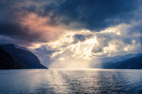 Norveç fiyordunda dramatik bir gökyüzü altında gün batımı
