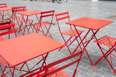 City cafe on the open air. Red metal chairs and tables outside with summer sun weather on the street. Design of furnitureset for summer cafe or restaurant.
