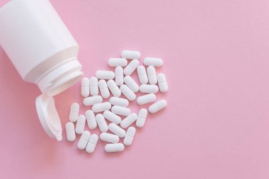 Pembe arka planda beyaz şişede bir sürü ilaç ve ilaç var. Sağlık sigortası konsepti. Metin için boşluk.