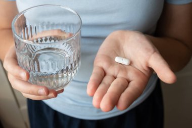 Hap ve bardak, elinde su olan bir çocuk. Eczaneden sağlık hizmeti. Çocuk hastalık yüzünden evde oturuyor..