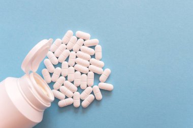 Mavi arka planda beyaz şişede bir sürü ilaç ve ilaç var. Sağlık sigortası konsepti. Metin için boşluk.