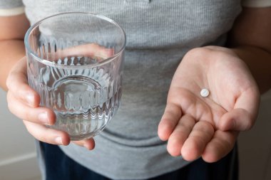 Hap ve bardak, elinde su olan bir çocuk. Eczaneden sağlık hizmeti. Çocuk hastalık yüzünden evde oturuyor..