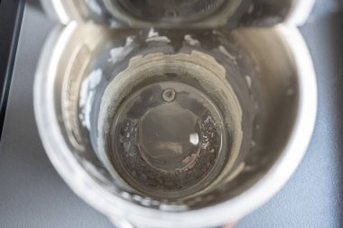 Kireçtaşı yüzeyi olan siyah elektrikli çaydanlık. Mutfaktaki metal çaydanlıkta sert su..