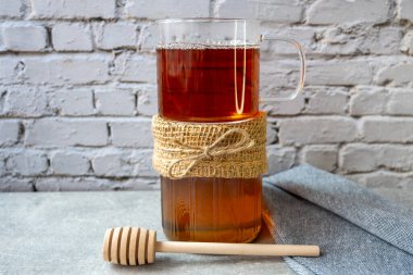 Balpetekli bal kavanozu, başlık ve tahta kaşık masada kalsın. Yiyecek konsepti.