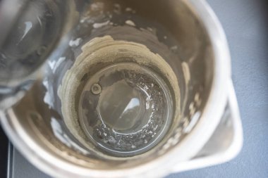 Kireçtaşı yüzeyi olan siyah elektrikli çaydanlık. Mutfaktaki metal çaydanlıkta sert su..