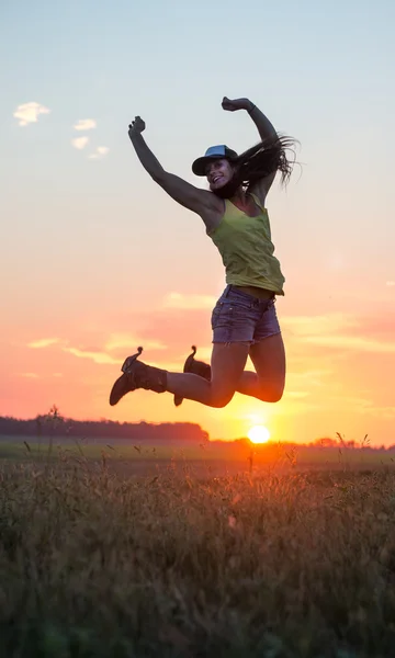 Vaqueira pulando de alegria ao pôr do sol — Fotografia de Stock