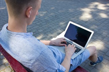 Dizüstü bilgisayarda yazan genç adam.