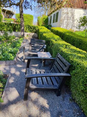 Satranç tahtası ve kırpılmış çitlerin yanında kırsal bahçe sandalyeleri