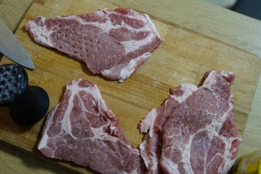  Adam ahşap masada kızarmadan önce domuz bifteği yiyor. Akşam yemeğinde et pişiriyor. Yüksek kaliteli HD görüntüler