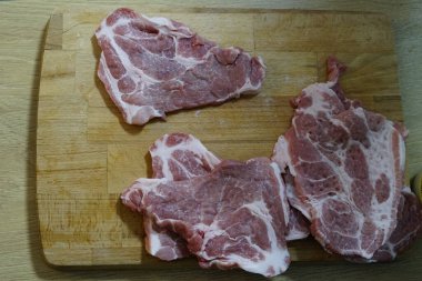  Adam ahşap masada kızarmadan önce domuz bifteği yiyor. Akşam yemeğinde et pişiriyor. Yüksek kaliteli HD görüntüler