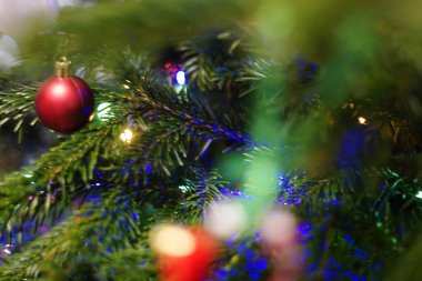 Renkli ışıklar ve süslerle süslenmiş yeşillik süsleme ağacının ve yılbaşı süsleriyle süslenmiş Noel Baba 'nın sıcak ve şenlikli atmosfer tatili kutlamalarının olduğu parlak kırmızı bayram süsünün yakın çekimi. Yüksek kalite fotoğraf