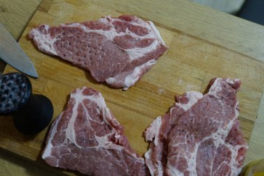 Mutfak şefi domuz bifteği pişirmeye hazır profesyonel aletlerle eti titizlikle buduyor. Yüksek kalite fotoğraf