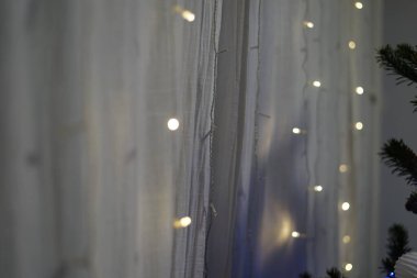 Aydınlatılmış şeffaf perdeler, çam gölgeli ve rahatlatıcı bir arka plan, yeni yıl ailelerinin sıcak atmosfer tatili kutlamaları. Yüksek kalite fotoğraf