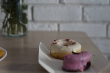 İki lezzetli çörek şu anda masa yüzeyine yerleştirilmiş dekoratif bir kağıt tabakta dinleniyor. Yakında birisi tarafından zevke getirilmeye hazır.