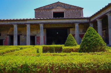 Roma 'nın Pompeii şehrinde güneşli bir günde sütunları, çatısı ve üst katıyla bahçeli ve bitkisel hayata sahip bir iç avlu..