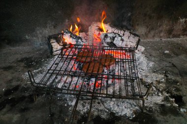 Hamburgerli ızgara ve bol kül. Izgara yanıyor ve et pişiyor..