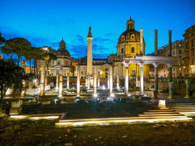 Trajan 'ın Forumu' nun arka planda ünlü sütunuyla bir yaz günü alacakaranlıkta, yapay ışıklarla aydınlatılan görüntüsü.