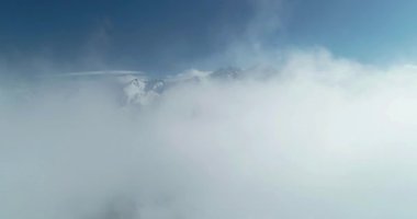 Bulutların üstündeki dağların havadan görünüşü. Dağlık alanın üzerindeki sisten uçuyorlar. Kuzey Kafkasya 'nın manzarası ve doğası