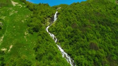 Yeşil bir ormanın ortasındaki dağ yamacında güzel bir şelale. Kuzey Kafkasya 'nın manzarası ve doğası