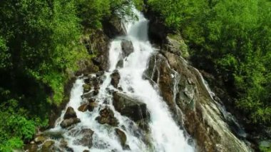 Yeşil bir ormanın ortasındaki dağ yamacında güzel bir şelale. Kuzey Kafkasya 'nın manzarası ve doğası