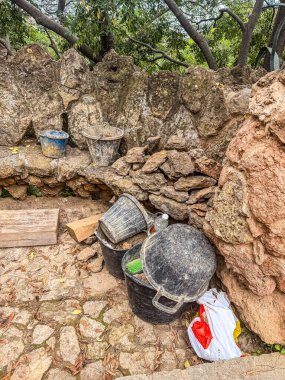 Yıpranmış plastik kovalar ve açık hava inşaat alanındaki kaba bir taş duvarın yanına yerleştirilmiş aletler yenileme malzemelerini gösteriyor yüksek kalite fotoğraf.