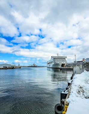 Modern yolcu gemisi kışın rıhtıma yanaşır ve iskelede kar yağar. Deniz taşımacılığı, seyahat endüstrisi, soğuk mevsim liman altyapısı yüksek kaliteli fotoğraf.