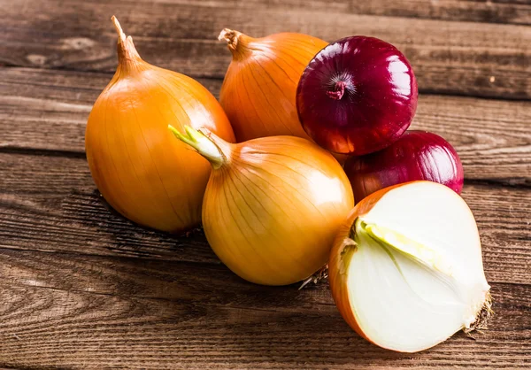 Kleurrijke uien op rustieke houten achtergrond — Stockfoto