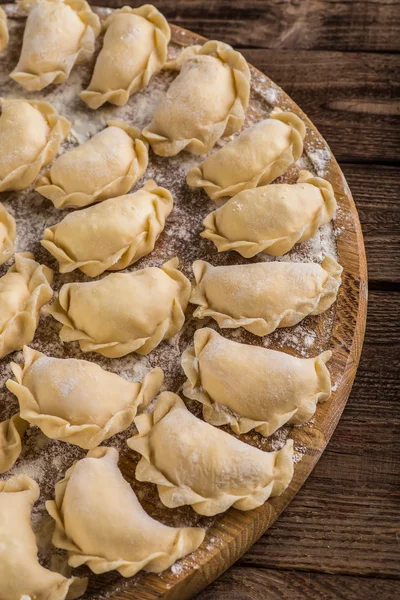 Esculpir pierogy, placa de corte, fazendo em uma mesa de madeira . — Fotografia de Stock