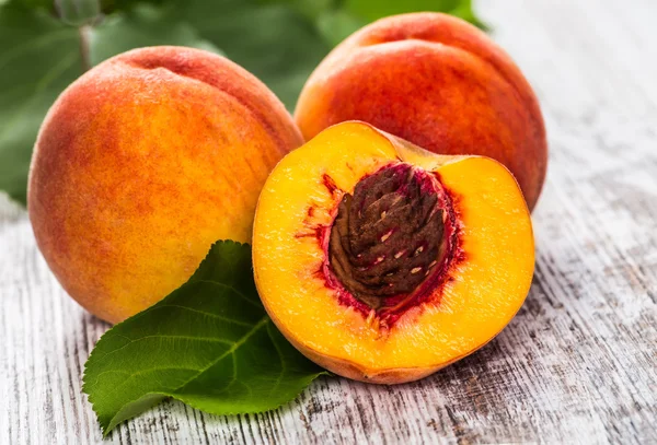 olgun şeftali ve yapraklar masada