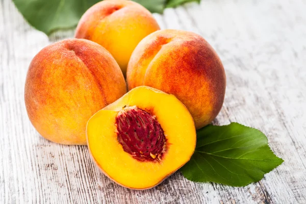 olgun şeftali ve yapraklar masada