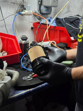 Eski bir Skoda arabasında yağ ve filtre değişimi. Rutin garaj bakımı sırasında motor yağı dökümünün, filtre yenilemesinin ve motor bölmesinin yakın çekim görüntüleri hassasiyete odaklan.