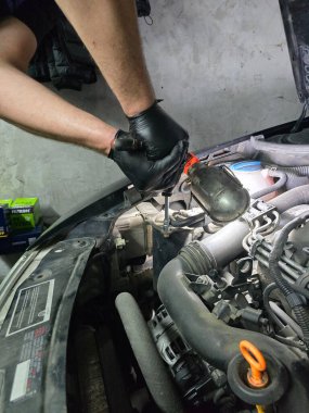 Eski bir Skoda arabasında yağ ve filtre değişimi. Rutin garaj bakımı sırasında motor yağı dökümünün, filtre yenilemesinin ve motor bölmesinin yakın çekim görüntüleri hassasiyete odaklan.