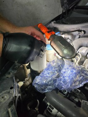 Eski bir Skoda arabasında yağ ve filtre değişimi. Rutin garaj bakımı sırasında motor yağı dökümünün, filtre yenilemesinin ve motor bölmesinin yakın çekim görüntüleri hassasiyete odaklan.