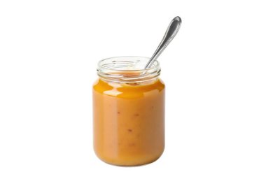 Kremalı portakal sosuyla dolu küçük bir cam kavanoz ve içine de sade beyaz bir zemin üzerine yerleştirilmiş gümüş bir kaşık.