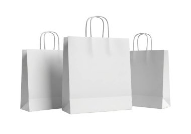 Görüntü, sapı sağlam üç adet özdeş beyaz kağıt alışveriş torbası gösteriyor. Düz beyaz bir zemine karşı yan yana dik konumda durarak, temiz ve minimalist bir görsel etki yaratırlar. Bu çantalar boş ve hazır görünüyor.