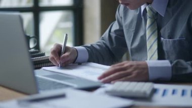 İşadamlarının yakınlaşması, masadaki hesap istatistiklerinin çizelgelerini gösteren kağıt üzerinde hesaplamalar yapmak ve yazmaktır.