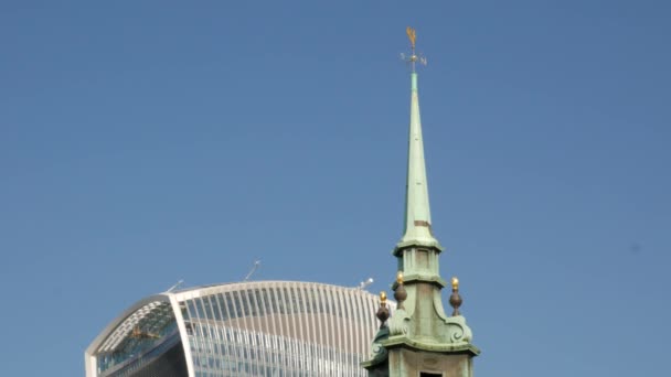 LONDON/UNITED KINGDOM 6TH SEPTEMBER 2015 - Tilt down the spire of the church of All Hallows by The Tower with the skyline of The City of London behind. Taken on a sunny autumn morning — Stock Video