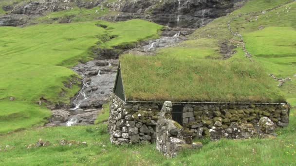 House with grass roof and waterfall behind in Saksun — Stock Video