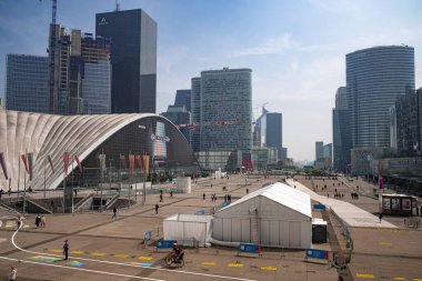 Paris 'teki La Defense iş bölgesinde açık alanda yürüyen insanlar. Arka plandaki Büyük Savunma Yayı. Mayday Holiday 'de çekildi