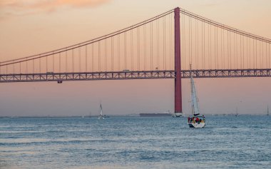 25 Nisan Köprüsü ve yatı denize açılmış Tagus Nehri. Arka planda İsa 'nın mabedi var.