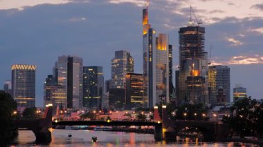 Alacakaranlıkta Frankfurt siluetinin dramatik ortalarında şehrin ışıkları açılacak. Alte Köprüsü 'nün altından geçen tekneler yaz boyunca çekildi.