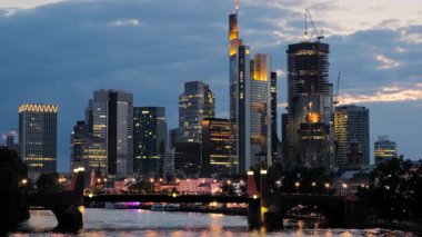 Şehrin ışıkları açıkken Frankfurt siluetinin çarpıcı mavi saat telefon klibi. Ana Nehir ön planda.