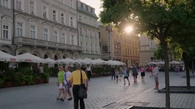 Krakow 'daki ana meydandaki Rynek Glowny' de eğlenen insanların günbatımı videosu.