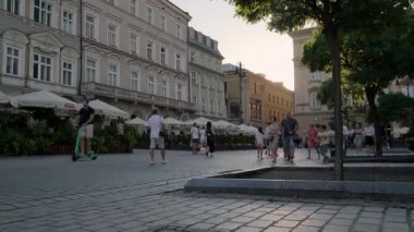 Krakow 'daki ana meydandaki Rynek Glowny' de günbatımının tadını çıkaran insanların kameraları yükseliyor.