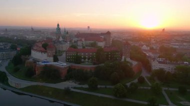 İnsansız hava aracı, muhteşem bir yaz gündoğumu sırasında Polonya 'nın Krakow kentindeki Wawel Kalesi' nin etrafında dönüyor. Vistula nehri ön planda.