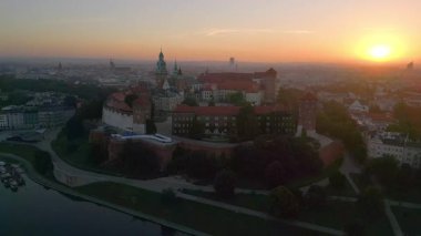 İnsansız hava aracı, muhteşem bir yaz gündoğumu sırasında Polonya 'nın Krakow kentindeki Wawel Kalesi' nin etrafında dönüyor. Vistula nehri ön planda.