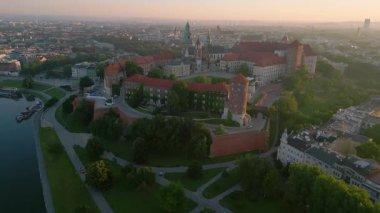 İnsansız hava aracı Wawel Kalesi 'nden geriye doğru uçarak Vistula Nehri' ni açığa çıkarıyor. Polonya, Krakow 'da bir yaz şafağında çekildi.