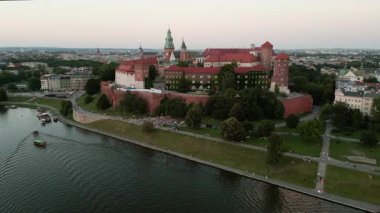 Sıcak bir yaz akşamında Krakow 'daki Wawel Kalesi' nde insansız hava aracı izleri var. Vistula Nehri boyunca seyahat eden tekneler.