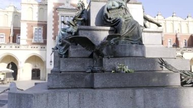 Kamera, Krakow 'un ana meydanı Rynek Glowny' deki Adam Mickiewicz Anıtı 'nı yukarı çekiyor